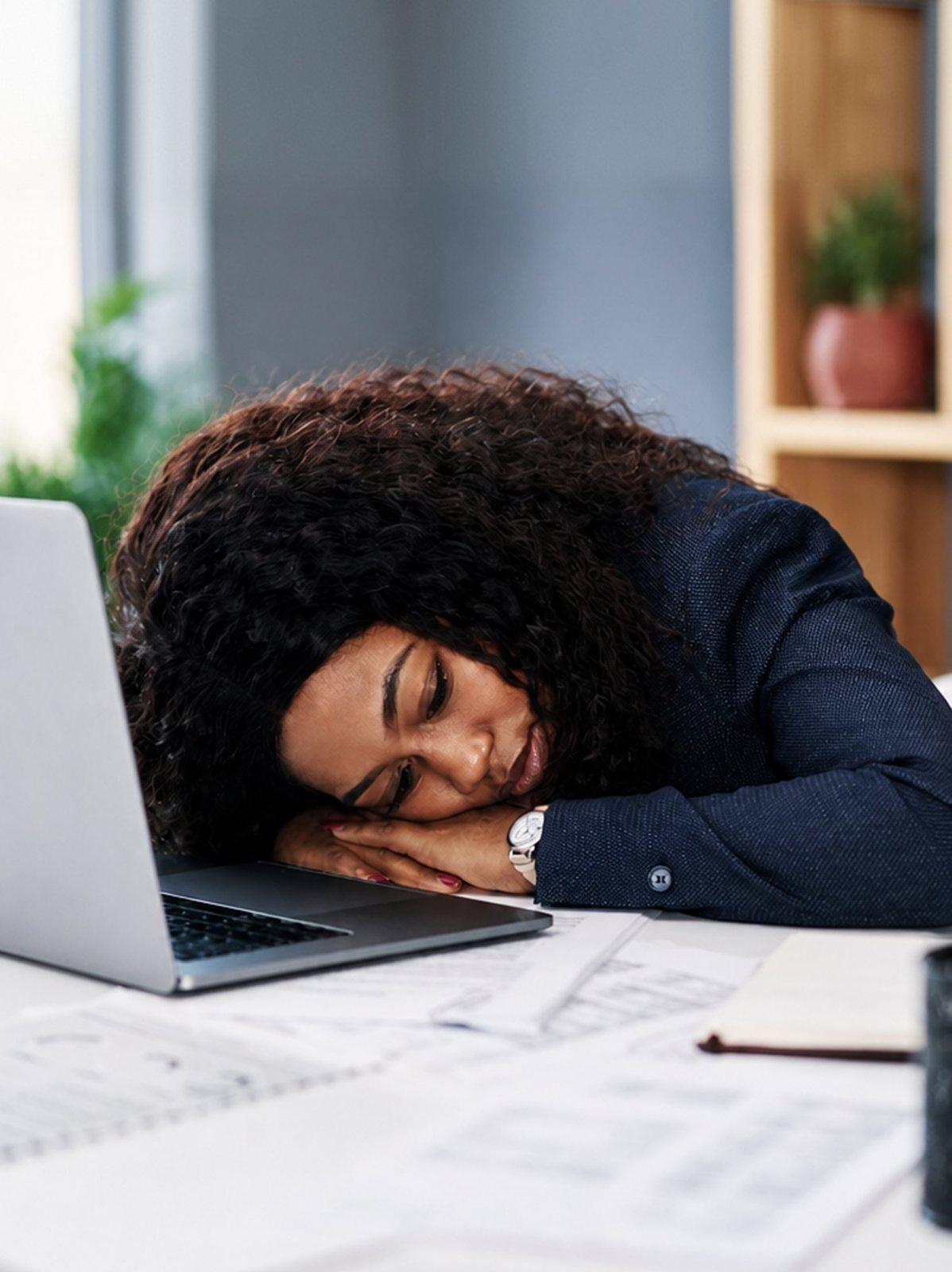 Exhausted woman resting her head on her desk